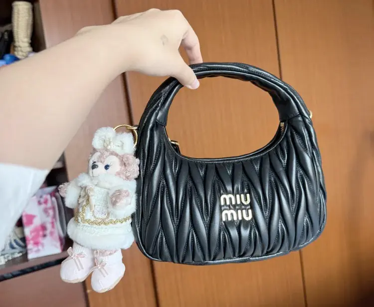 Close-up of hand carrying black replica Miu Miu Wander Hobo bag showing strap details